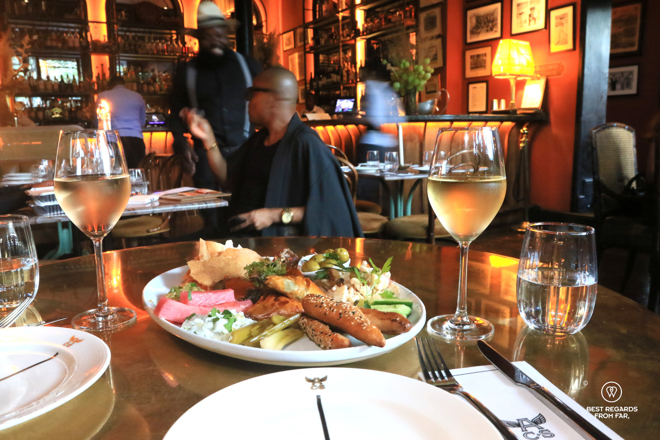 A plate of mezze at the Athletic Club and Social with patrons and waiters in the background.