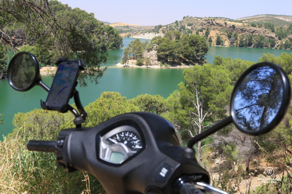 Turquoise lake, trees and a scooter in the foreground.