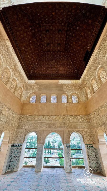 Carved calligraphy on the walls of the Alhambra with a view on Granada.