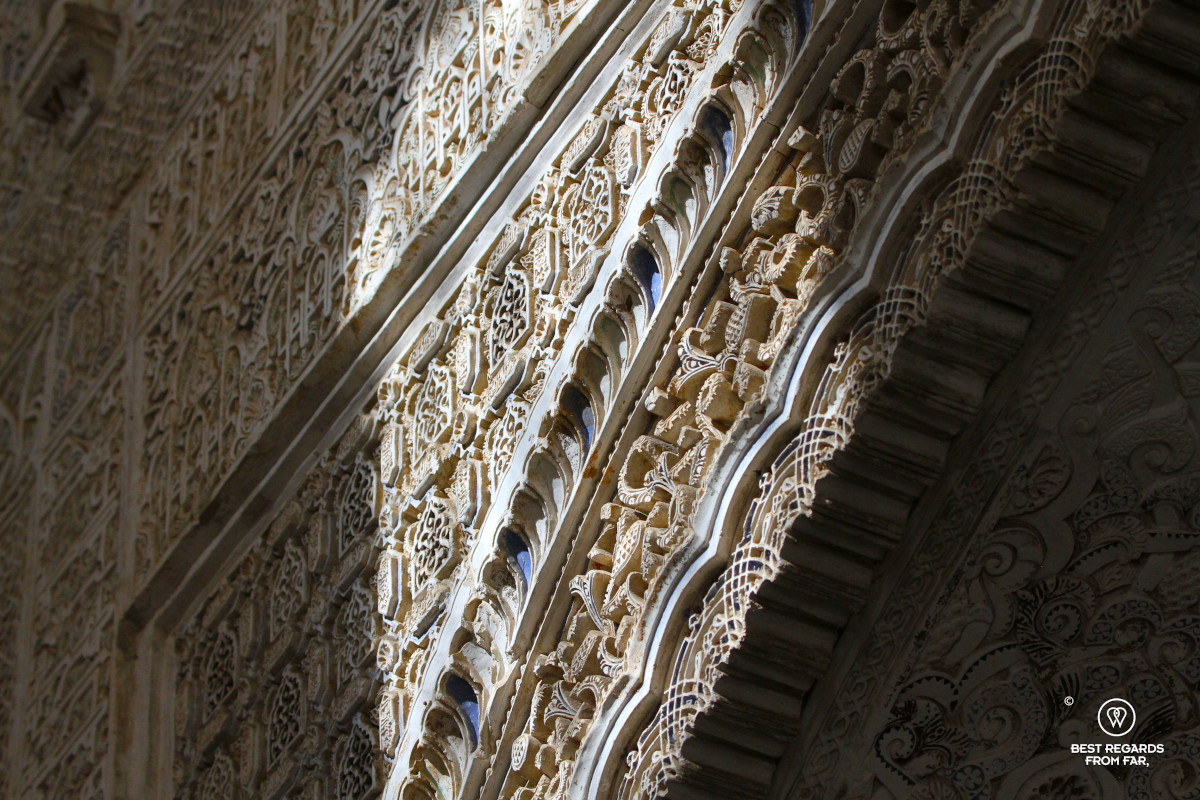 Details of carved calligraphy lit by sunlight on the walls of the Nasrid Palace at the Alhambra in Granada.