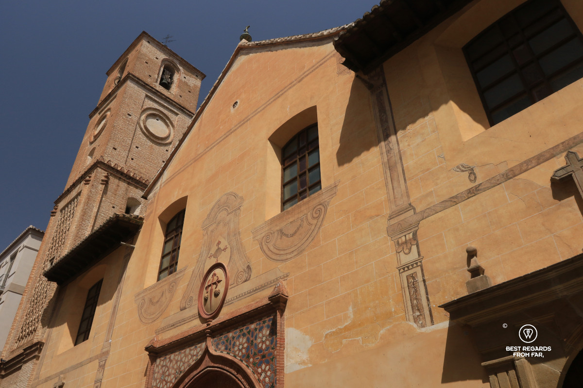 The façade of the Santiago Church in Malaga with a bright blue sky.