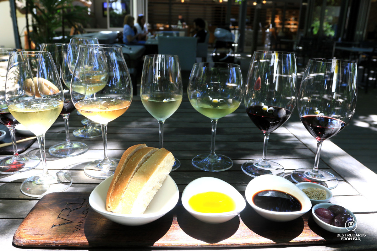 Wine tasting with 6 glasses of wine and a wooden tray with bread, olive oil, balsamico and olives.
