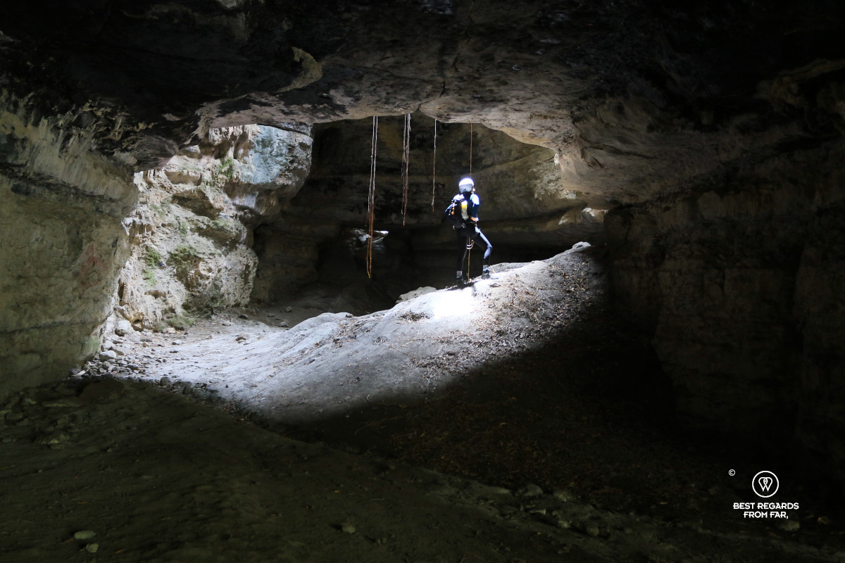 Woman wearing a backpack and white helmet in a cave.