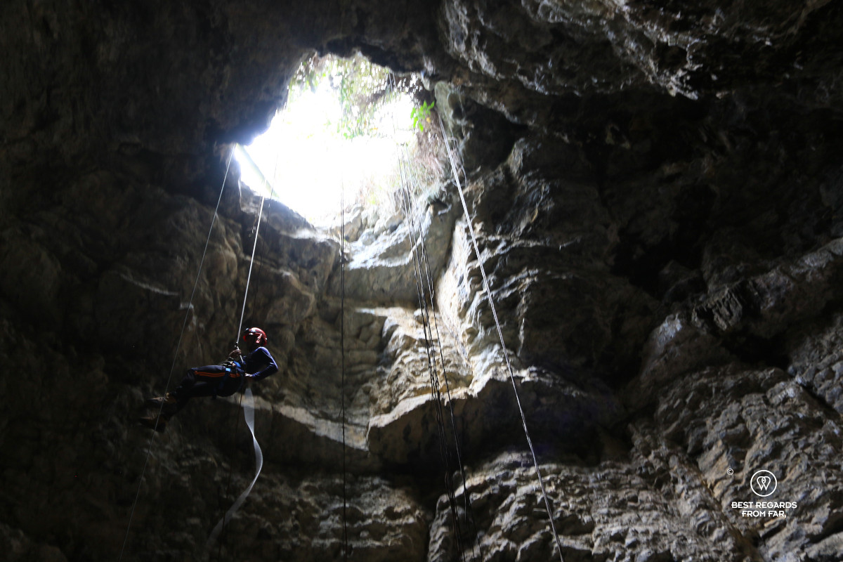 Man rappelling down into a cave.