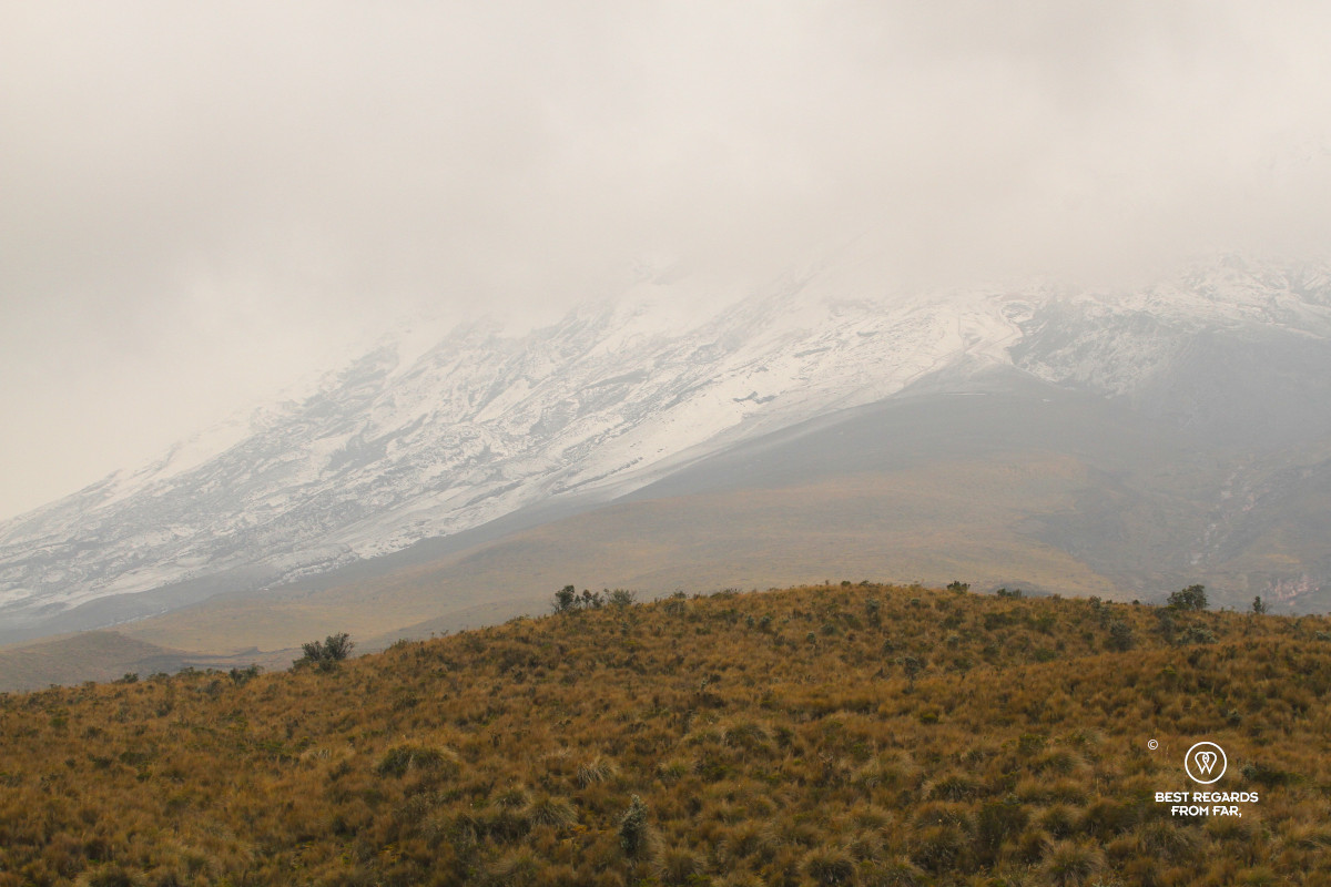 The cone of Cotopaxi Volcano hidden in clouds and covered in snow.
