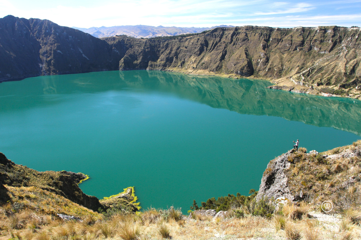 A hiker overlooking the Quilotoa Crater Lake with its emerald water in Ecuador.