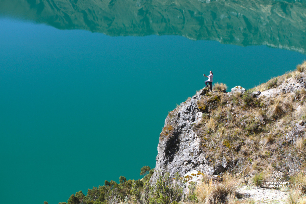 Zoom on a hiker overlooking the Quilotoa Crater Lake with its emerald water in Ecuador.