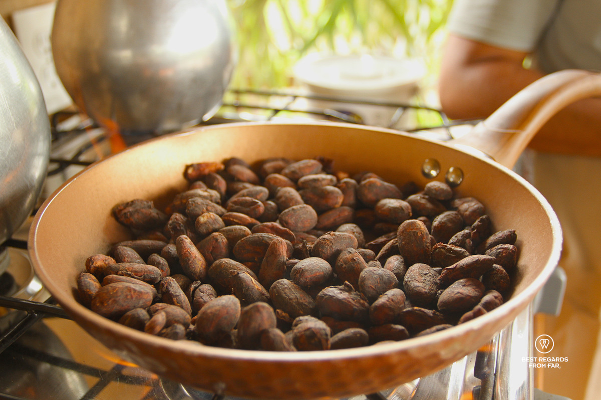 Roasting cacao beans in a copper pan on a gas stove.