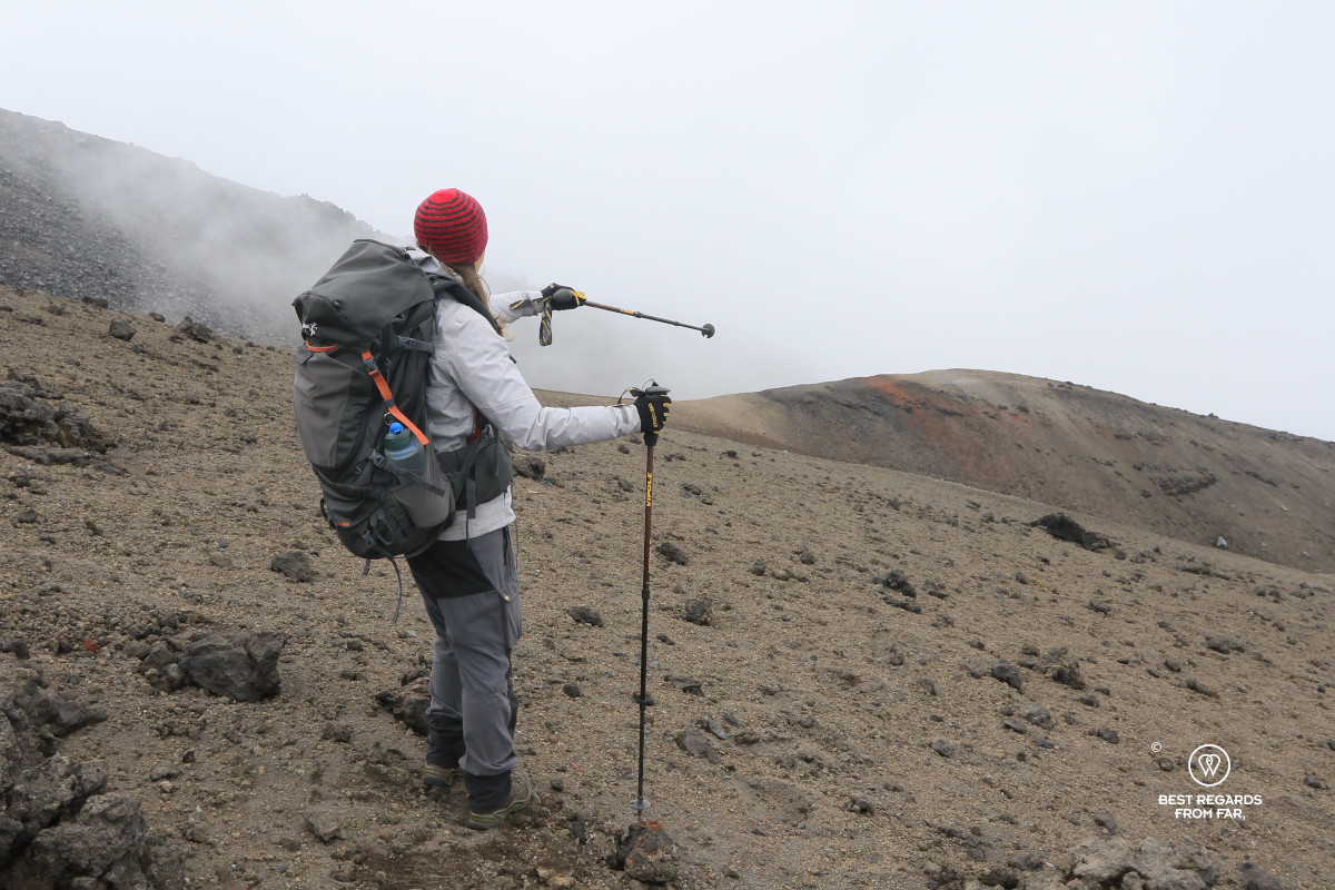 Hiker pointing with a hiking pole to the volcanic slope of Cotopaxi.