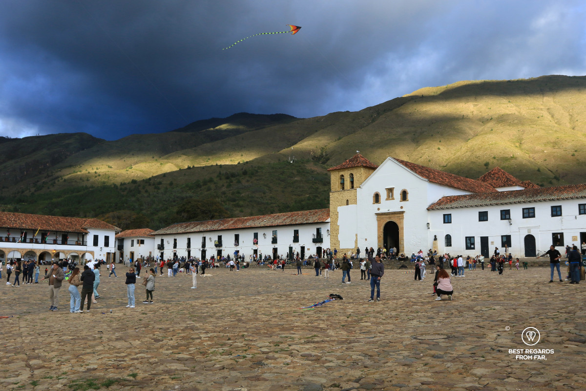Large cobblestoned square with mountains in the background and dark skies.