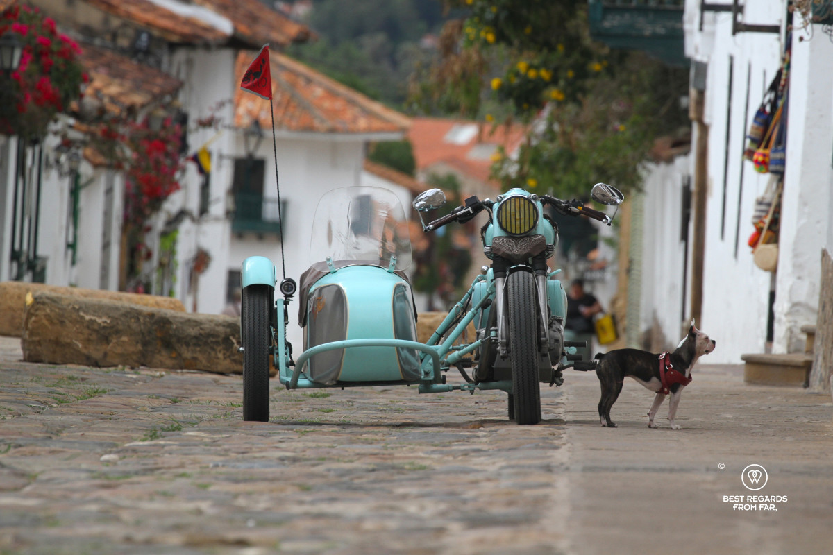 Vintage turqoise motorcycle with a side car on a cobblestoned street.