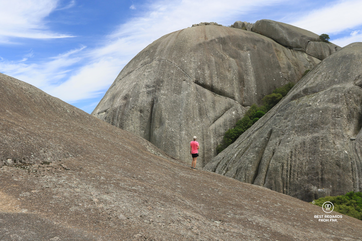 Hiker towered by a gigantic granite boulder on Bretagne Rock in Paarl in South Africa.