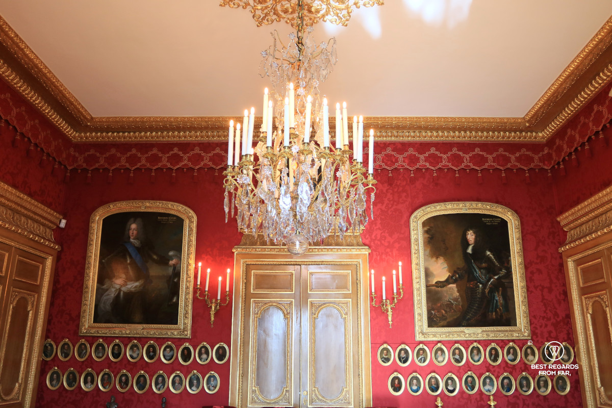 Portraits of the Condé's hung on a red wall in the private apartments of the Castle of Chantilly.