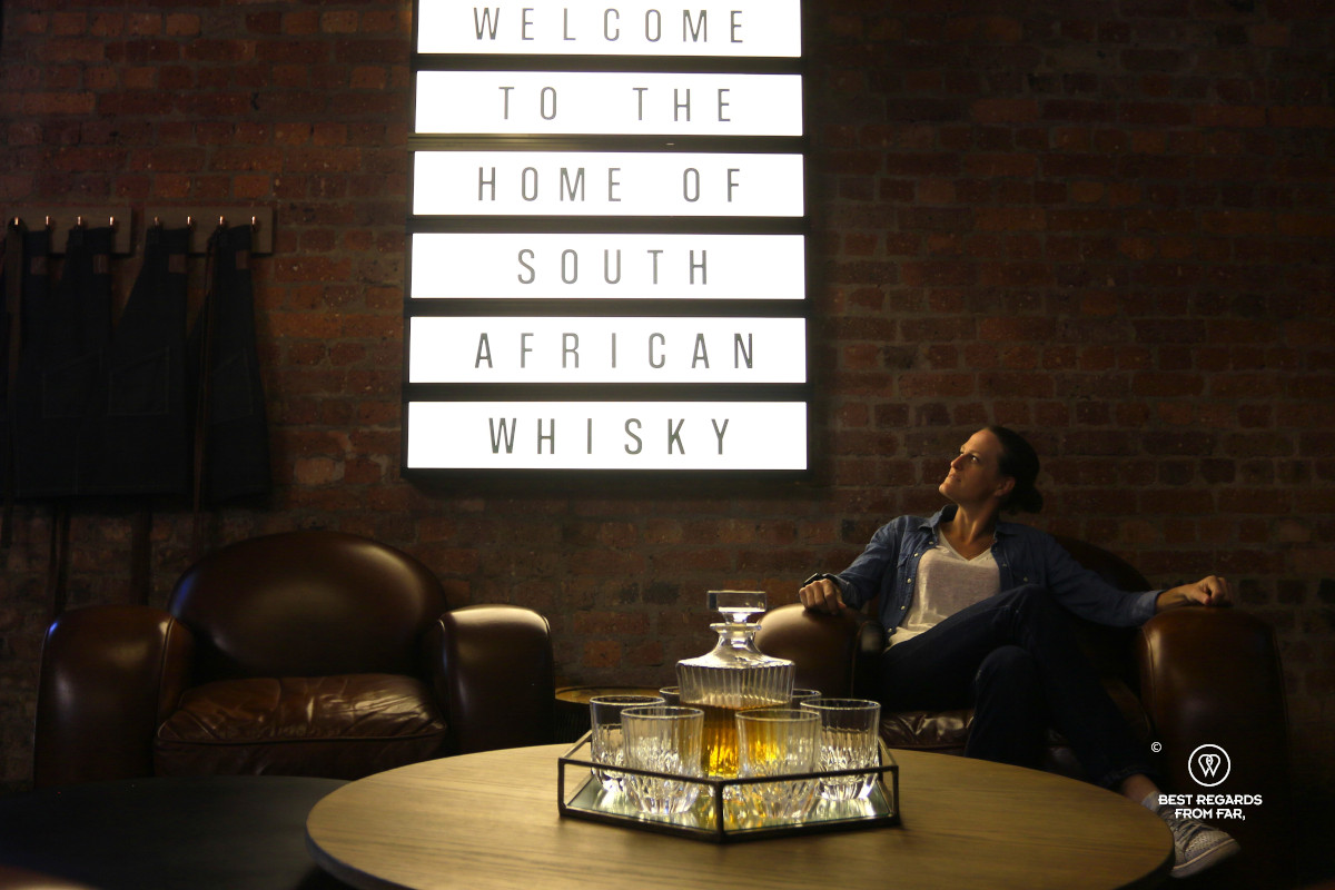 Woman seating by a lit sign at the James Sedgwick Distillery.