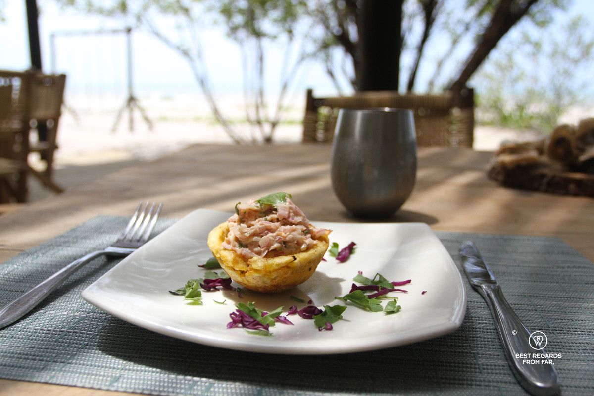 Clam ceviche in patacon on a wooden table by the beach.