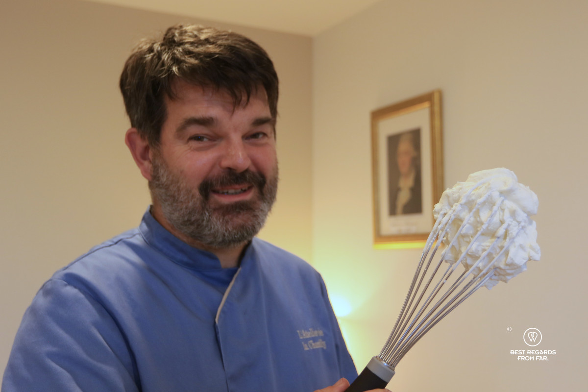 Bertrand Alaime, owner of L'Atelier de la Chantilly, holding a whisk with whipped Chantilly cream.