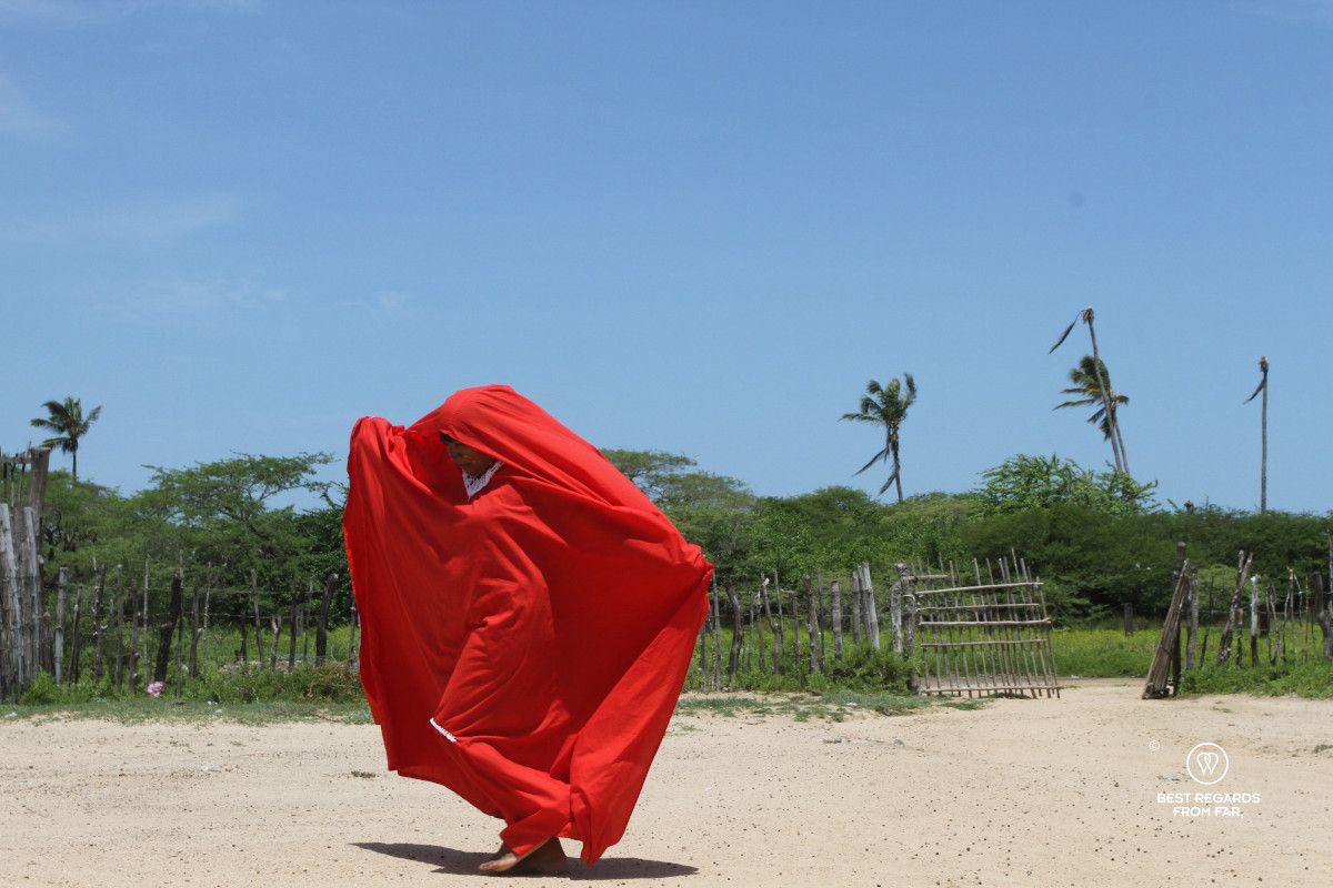 Wayuu woman dancing the yonna dance in a red dress in a rancheria in SFF Los Flamencos.