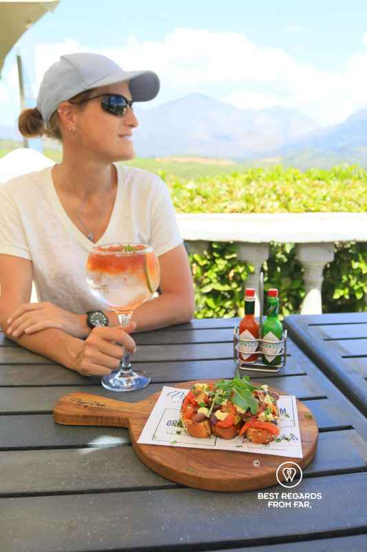 Woman holding a mocktail with a bruschetta on the table at Pizza Vista in Wellington.