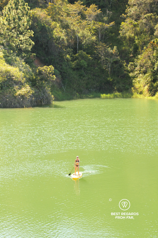 Woman stand up paddling on the emerald waters of the Guatape Lake.
