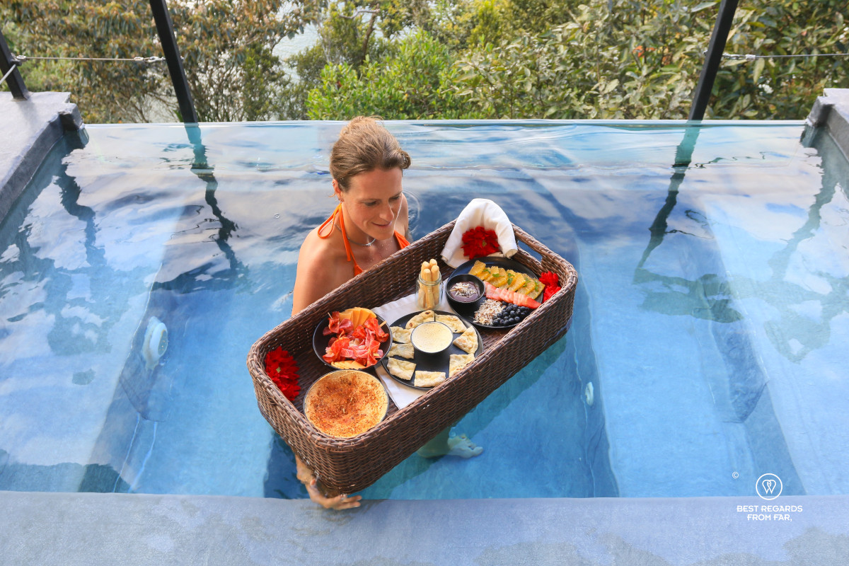 Woman holding a floating basket tray with breakfast in the private pool at Bosko.