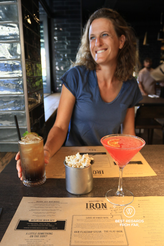 Woman having a cocktail at a table at Iron Steak and Bar Restaurant in Cape Town.