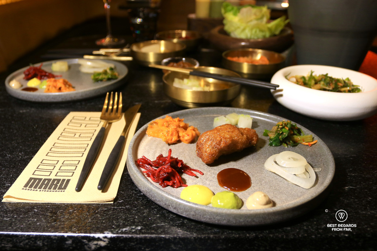 Fried chicken in a plate circled by Korean sides at Maru restaurant in Cape Town.