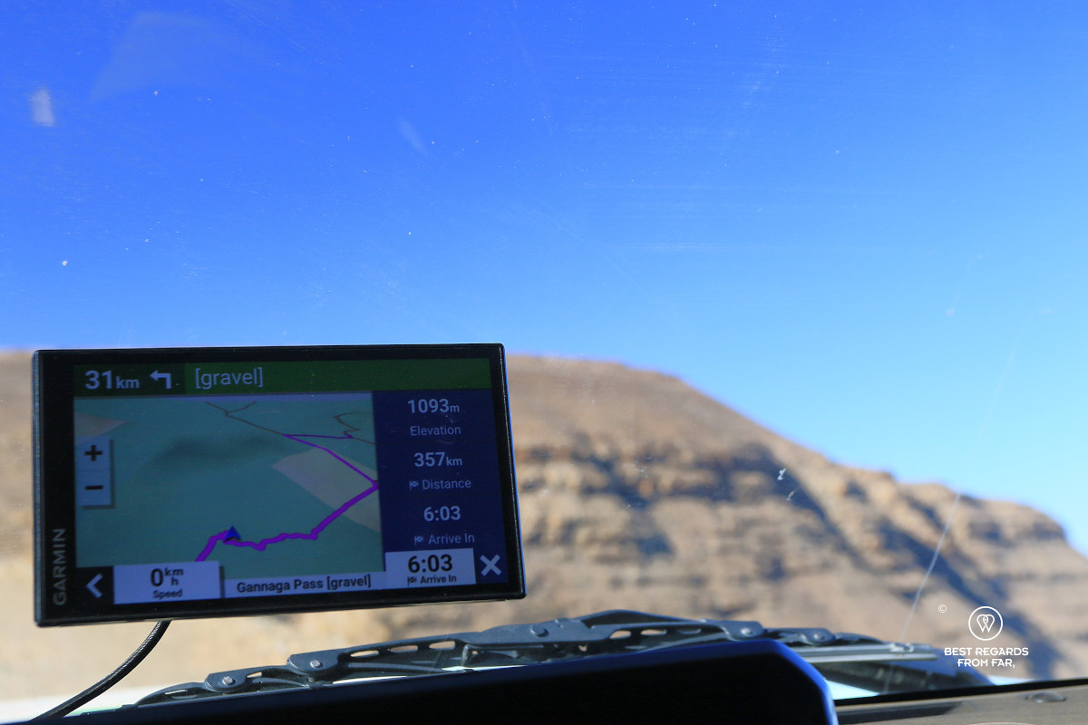 Garmin GPS attached to the windscreen of a car with a mountain in the background.