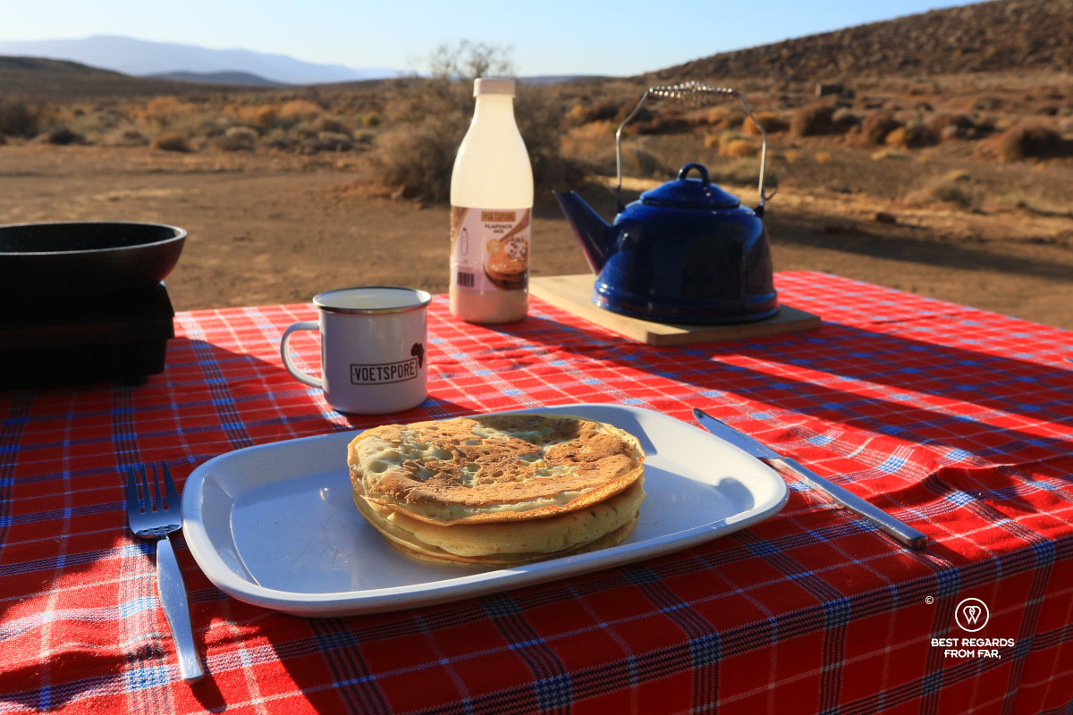 Flapjacks, coffee and an induction stove on a table with a red tablecloth in the outdoors.