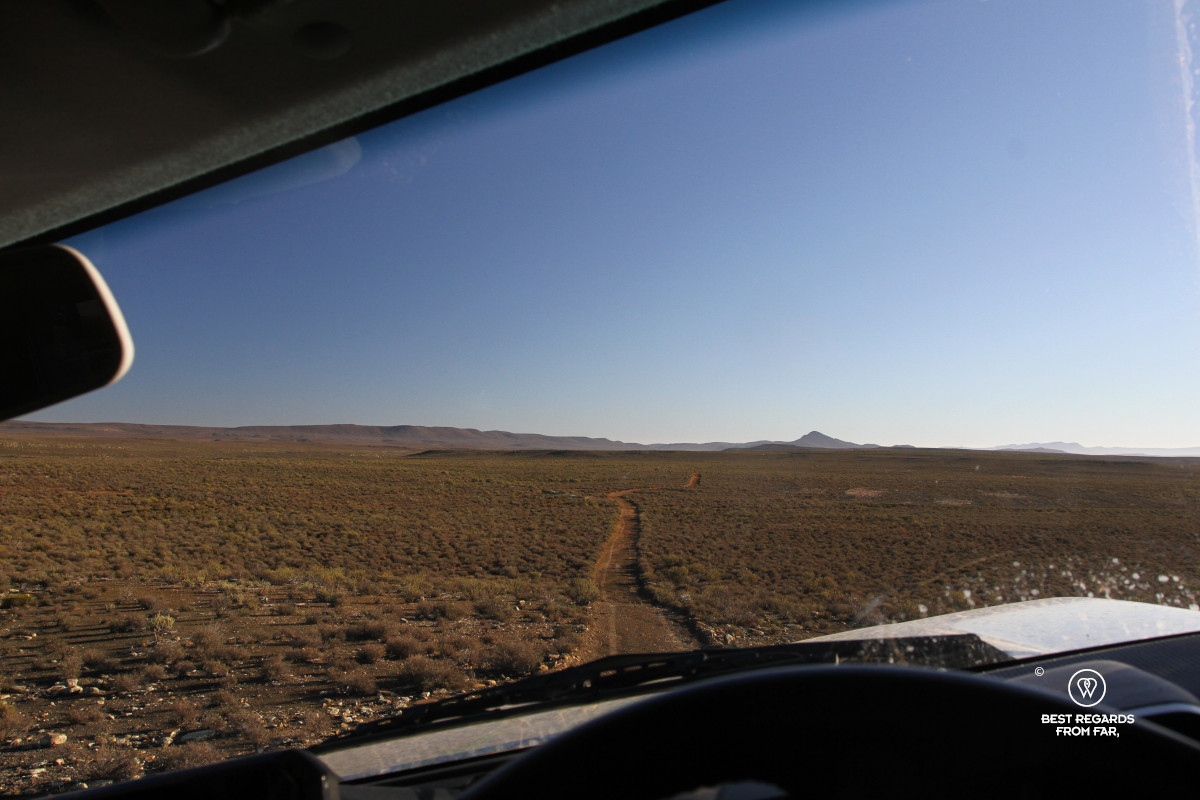 Horizon framed through the windscreen of a tilted car driving over a bumpy road.