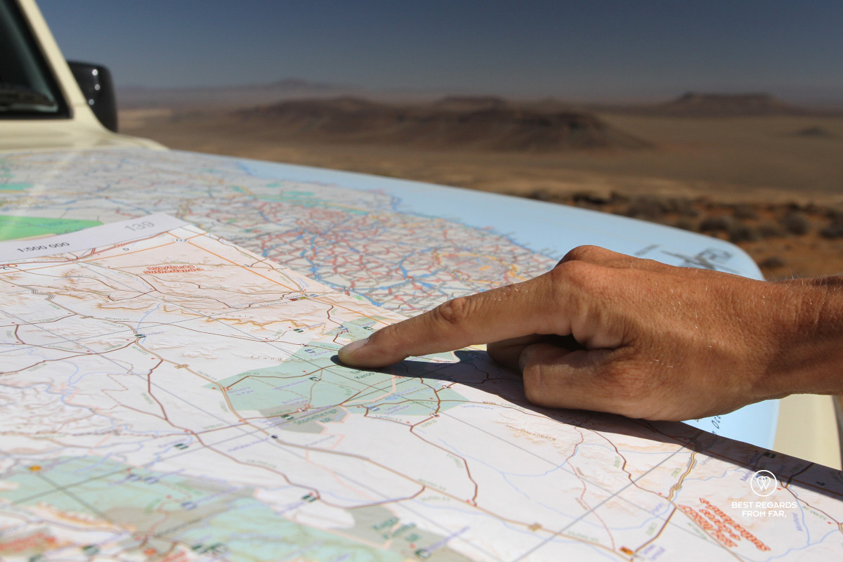 Close-up of a finger pointing to a location in the atlas on the car.
