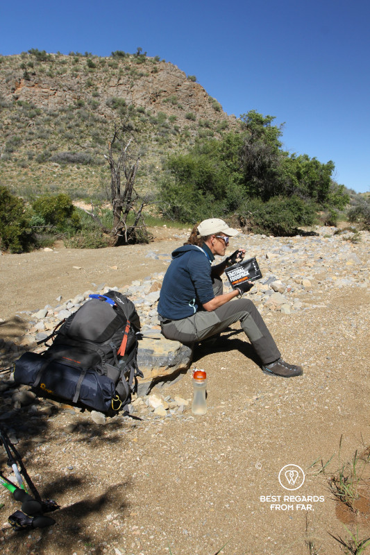 Author Marcella van Alphen enjoying a tactical foodpack lunch in a dry riverbed during a long hike.