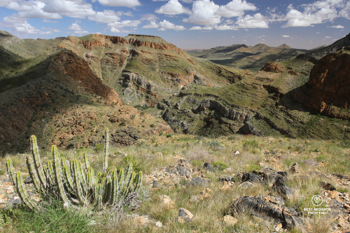 Deep canyons, rugged red stones of the Naukluft mountains and the red dunes of the Sossusvlei in the background.