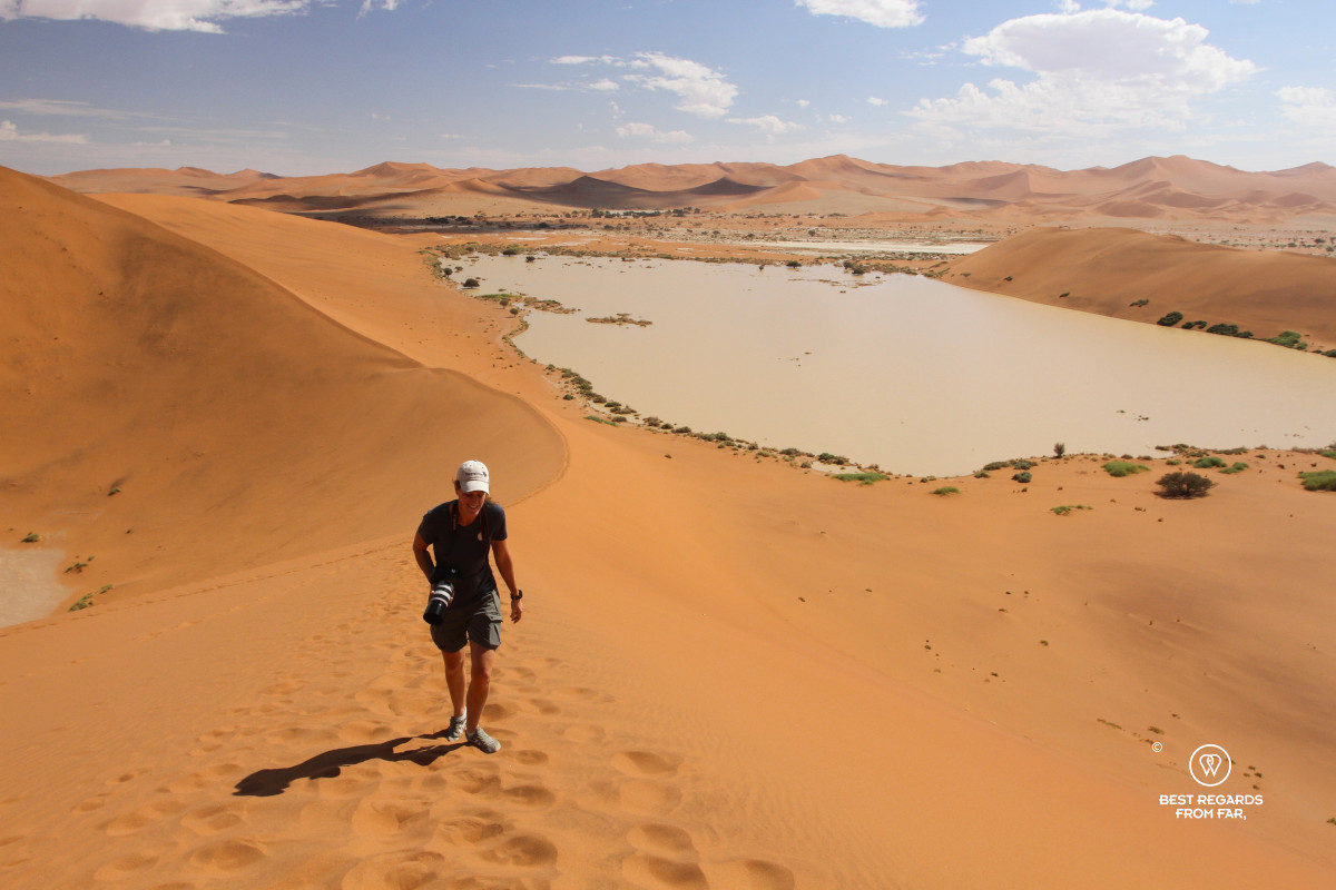 Photographer Marcella van Alphen climbing up a dune with the dessert flooded in the background.