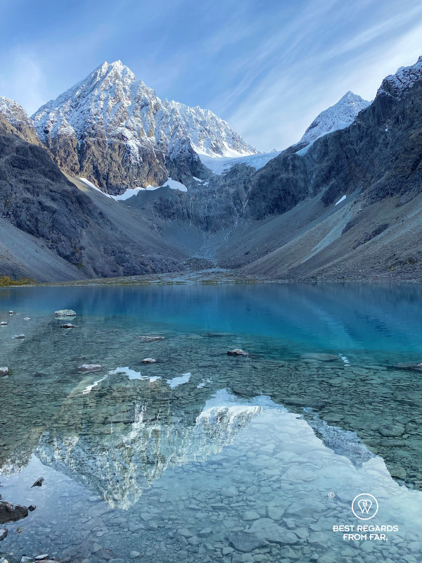 The Blue Ice Lake in the Lyngen Alps with snowy peaks reflected in its turquoise water.