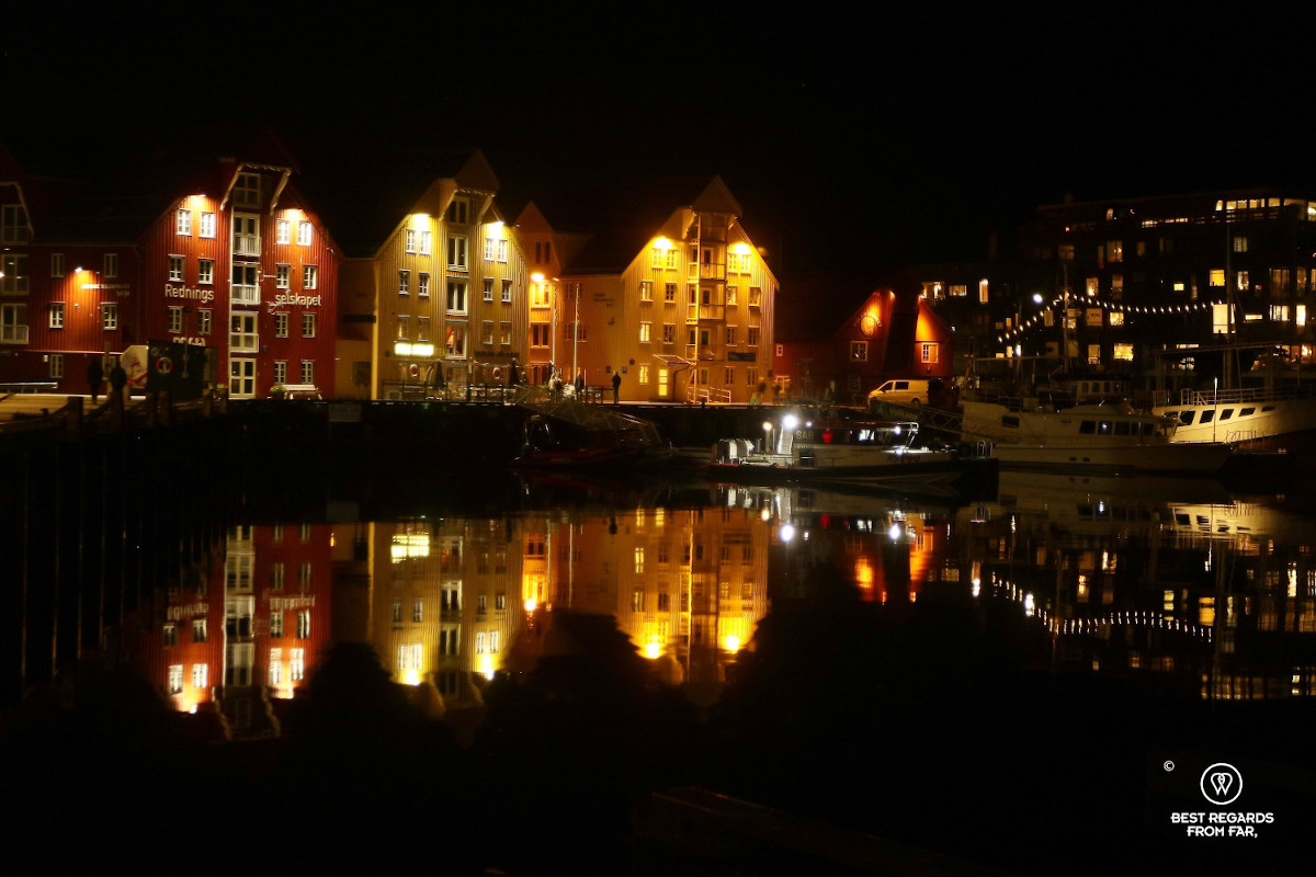 Bryggen in Tromso by night with reflections in the water.