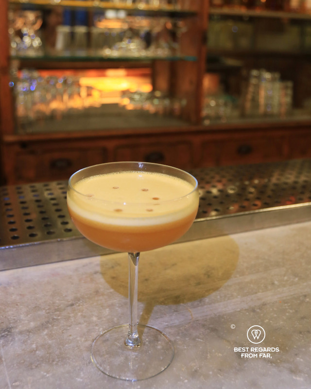 Cocktail with a foamy top on a bar counter.