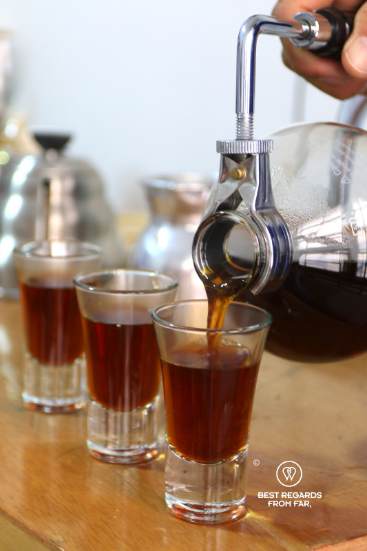 Pouring freshly brewed coffee into tasting glasses.